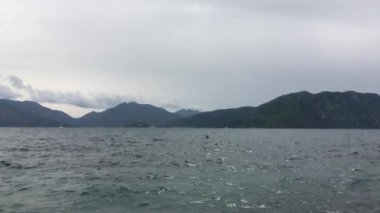 Denizin ve dağların farklı yükseklikleri, gri gölgeler, büyüleyici su dalgaları, hipnotik, sakinleştirici doğa etkileri.