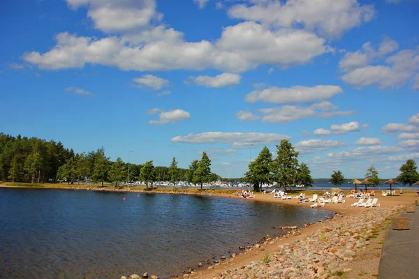 nature of Finland, lake with clear water, sandy beach, sun loungers, pine trees, beautifully located Cumulus clouds