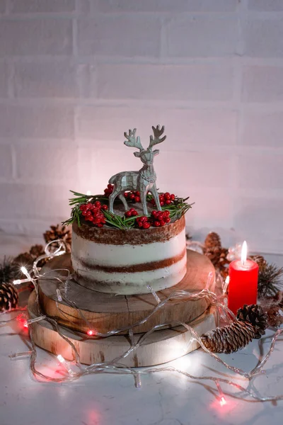 Christmas chocolate vanilla cake. Rustic homemade cake. Piece of cake. Vegan raw cake. Decorated rosemary and christmas tree. Lights and sparkler. Candle and garland on the background.