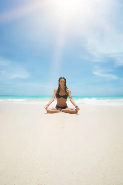 Yoga woman meditating at serene tropical beach, morning zen mediation. Girl relaxing in lotus pose in calm