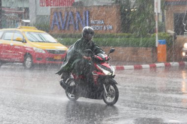 Pattaya Tayland - Mayıs 2018 yaklaşık. Motosiklet sürücüsü ağır tropik fırtına yağmur sırasında ıslak Tay sokaklarda. Muson sezonu. Gün Editör atış