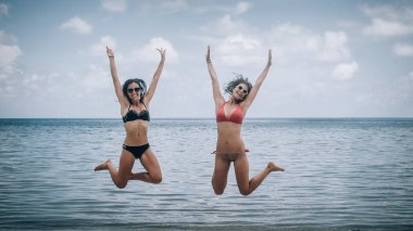 İki mutlu kız tropik sahilde atlama. Koh Tao, Tayland