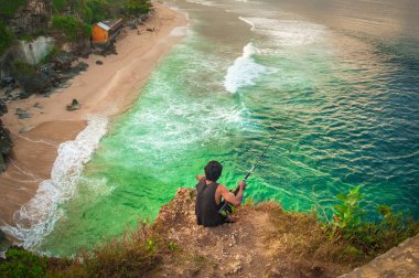 Bali, Endonezya - 30. Nisan 2018. Adam Hint deniz kenarı uçurumun kenarında balık tutma. Gün Editör atış