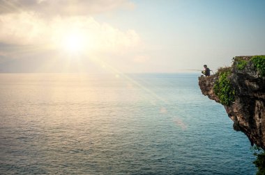 Bali, Endonezya - 30. Nisan 2018. Adam Hint deniz kenarı uçurumun kenarında balık tutma. Gün Editör atış