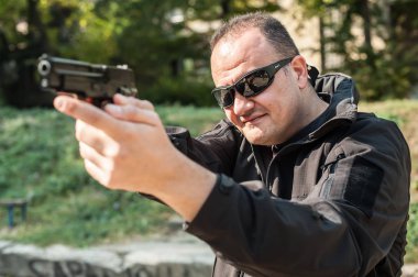 Saldırganın korumak için polis ajanı ve işaret koruma tabanca. Silahı doğrult hedefleyen önden görünüm açık