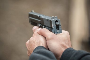 Tetikçi holding silah görünümünü el detay ve silah, yakın çekim. Çekim aralığı