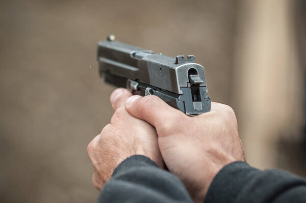 Вид стрелка, держащего в руках пистолет и стреляющего, крупным планом. Дальность стрельбы
