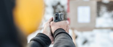 Ayrıntı arka tetikçi holding silahı elinde görüntülemek ve hedef üzerinde çekim kapatın. Çekim aralığı