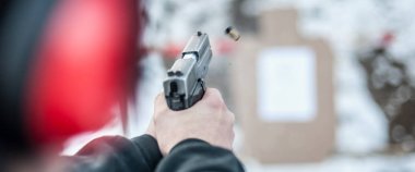 Ayrıntı arka tetikçi holding silahı elinde görüntülemek ve hedef üzerinde çekim kapatın. Çekim aralığı