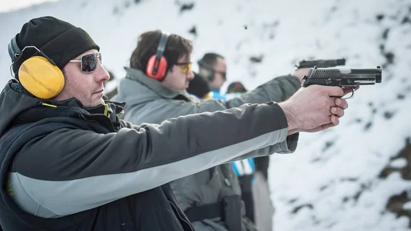 Group of civilian practice gun shoot on target on outdoor shooting range. Civilian team weapons training