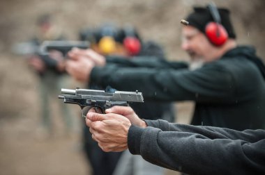 Group of civilian practice gun shoot on target on outdoor shooting range. Civilian team weapons training clipart