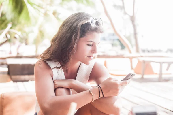 Junge Frau mit Smartphone entspannt am tropischen Strand — Stockfoto