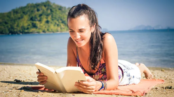 Mulher ler livro enquanto aprecia a luz do sol na praia — Fotografia de Stock