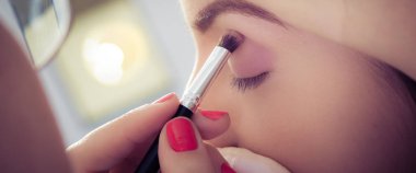 Kadın yüz cilt üzerinde göz farı tozu uygulayarak ellerin closeup