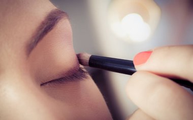 Kadın yüz cilt üzerinde göz farı tozu uygulayarak ellerin closeup