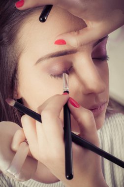 Kadın yüz cilt üzerinde göz farı tozu uygulayarak ellerin closeup