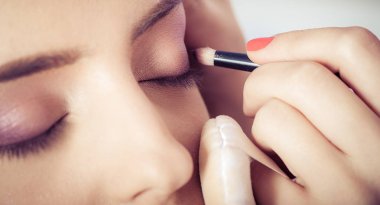 Kadın yüz cilt üzerinde göz farı tozu uygulayarak ellerin closeup