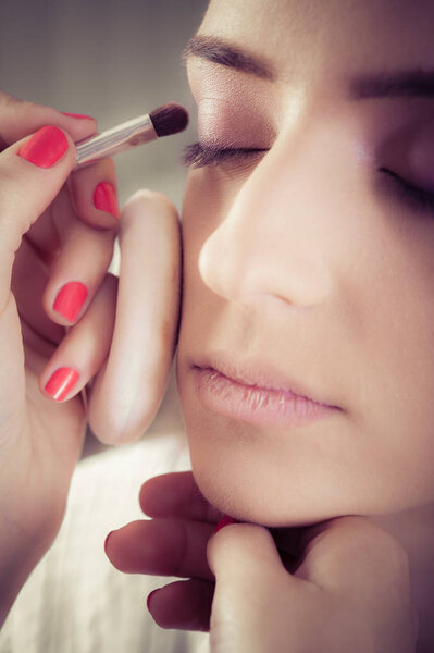 Закрытие рук, нанесение теневого порошка на женскую кожу лица
