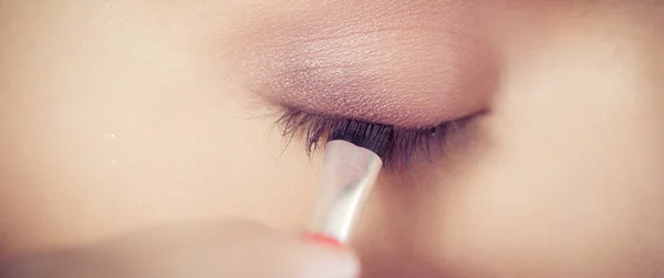 Closeup of hands applying eyeshadow powder on female facial skin — Stock Photo, Image