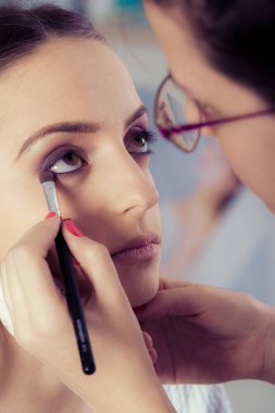 Kadın yüz cilt üzerinde göz farı tozu uygulayarak ellerin closeup