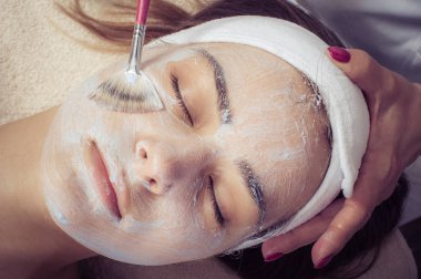 Spa salonunda kadın için yüz güzellik maskesi uygulayan kozmetikçi