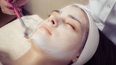 Spa salonunda kadın için yüz güzellik maskesi uygulayan kozmetikçi