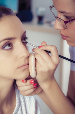 Kadın yüz cilt üzerinde göz farı tozu uygulayarak ellerin closeup