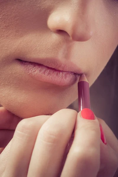 Primer plano de las manos aplicando lápiz labial sobre la piel facial femenina — Foto de Stock