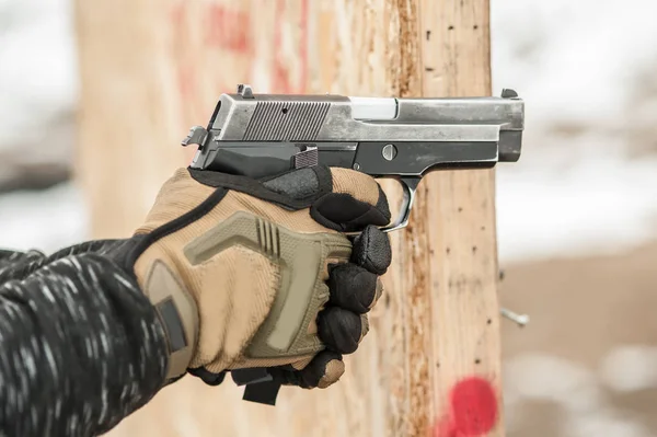 Close-up detail view of hands in gloves holding gun — Stock Photo, Image