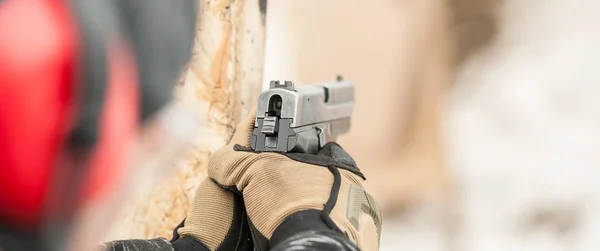 Close-up detail view of hands in gloves holding gun — Stock Photo, Image
