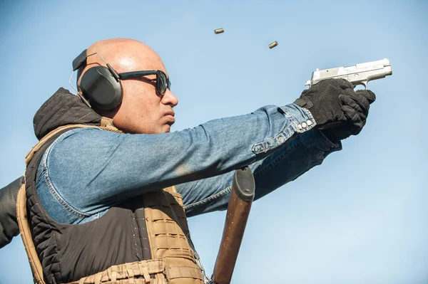Shooter holding gun in hand and shooting. Close-up detail view — Stock Photo, Image