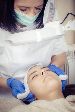 Genç bir kadın güzellik salonunda kozmetik tedavi görüyor.