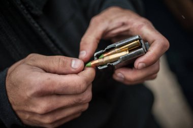 Asker elleri şarjöre makineli tüfek mermileri yükler.