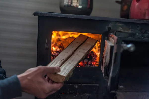 Homem colocando log para fogão a lenha — Fotografia de Stock