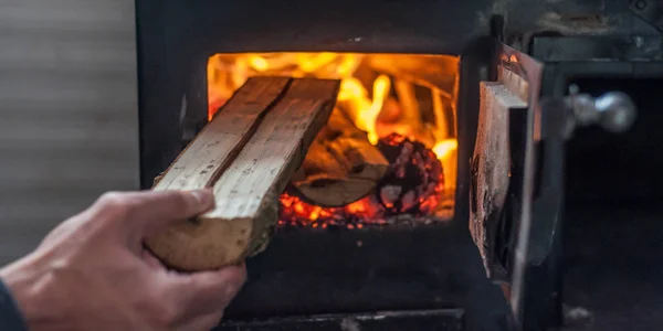 Άνθρωπος βάζοντας log σε ξύλινη σόμπα φωτιά — Φωτογραφία Αρχείου