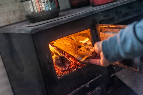 Man putting log to wood burning stove — Stock Photo, Image