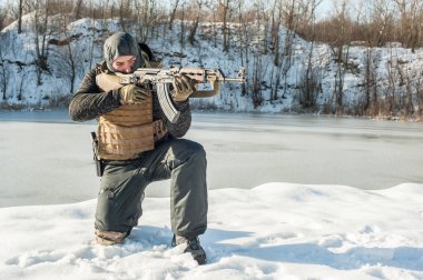 Asker çömelmiş pozisyonda tüfekmakineli tüfekten ateş