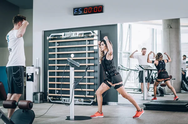 EMS électrostimulation femmes exercices avec entraîneur dans la salle de gym moderne — Photo