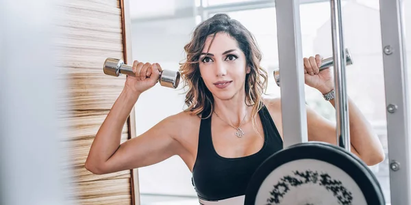 Atractiva mujer fitness muscular haciendo ejercicio con pesas —  Fotos de Stock