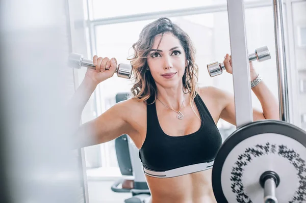 Atractiva mujer fitness muscular haciendo ejercicio con pesas —  Fotos de Stock