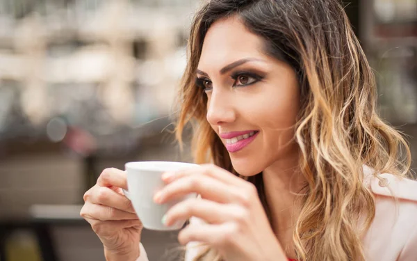 Portrait of woman sitting in outdoor cafe and drinking coffee — Stock Photo, Image