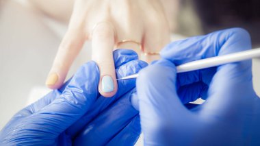 Manikürcü kadın güzellik salonunda oje sürüyor.