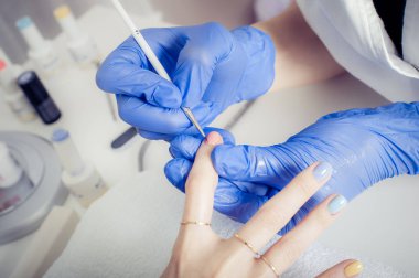 Manikürcü kadın güzellik salonunda oje sürüyor.