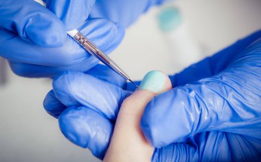 Manikürcü kadın güzellik salonunda oje sürüyor.