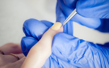 Manikürcü kadın güzellik salonunda oje sürüyor.