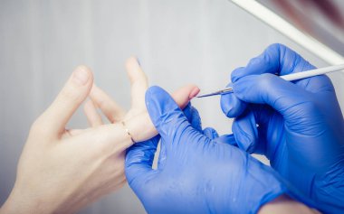 Manikürcü kadın güzellik salonunda oje sürüyor.