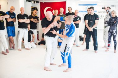 Kapap eğitmenken Akiyama bıçaklı saldırıya karşı silahsızlanma teknikleri gösteriyor