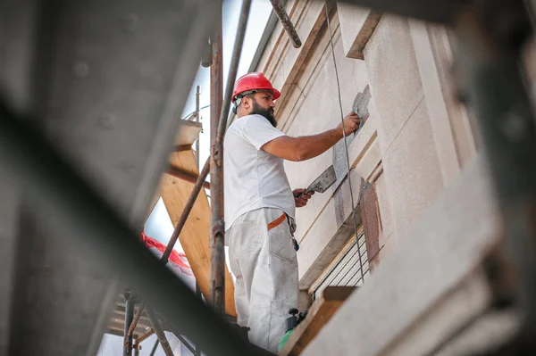 Mann steht auf Gerüst und restauriert alte Hausfassade — Stockfoto