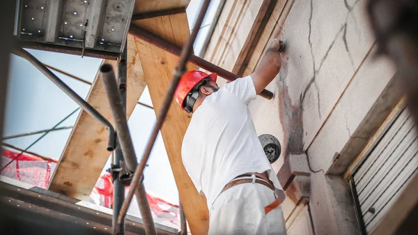 Mann steht auf Gerüst und restauriert alte Hausfassade — Stockfoto