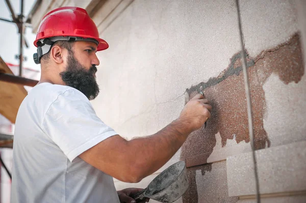 Männlicher Arbeiter verputzt alte Hauswand mit Zementputzmischung — Stockfoto